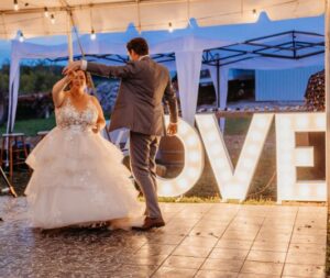 married couple dancing in front of love marquee letters