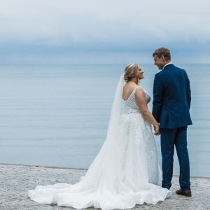 bride and groom smiling at each other while standing in front of Lake Erie on their wedding day