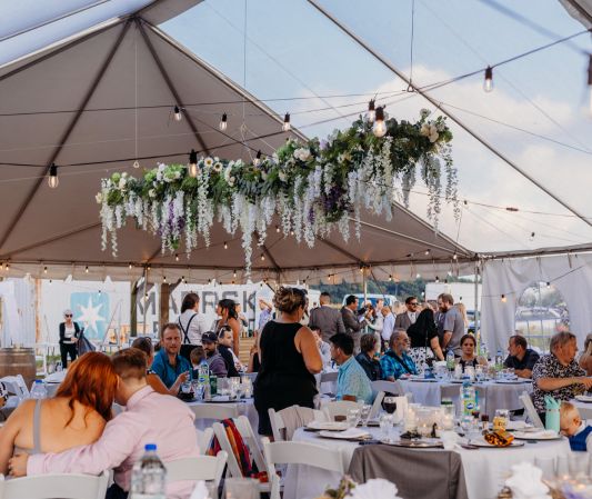 wedding reception clear top tent with guest tables and hanging florals and string lights